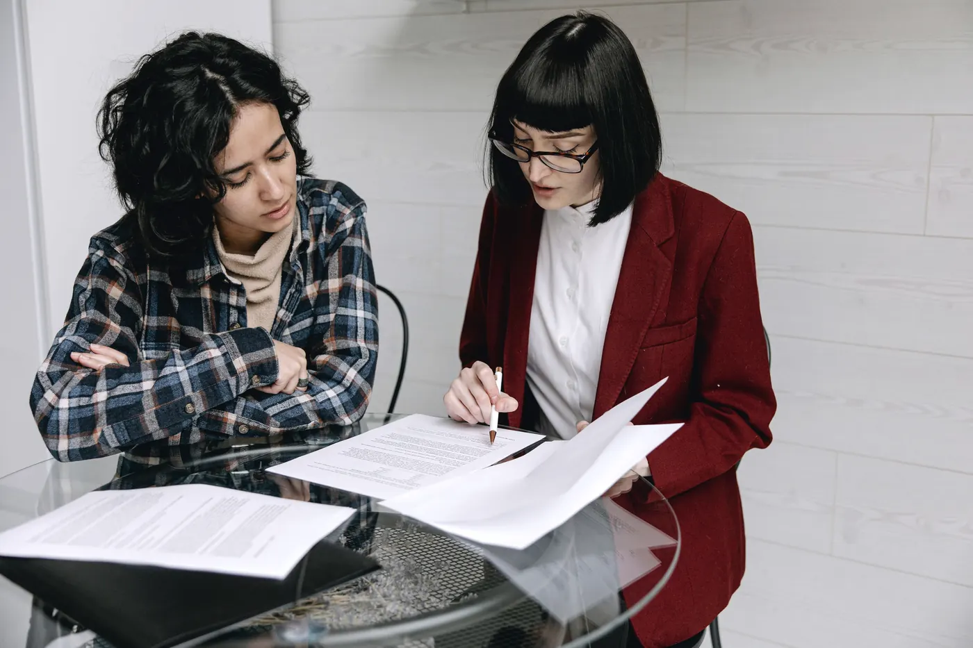 Deux femmes qui relisent ensemble des documents sur une table de verre
