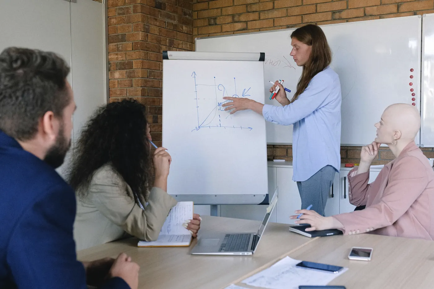 Formatrice qui explique un schéma au tableau devant une équipe